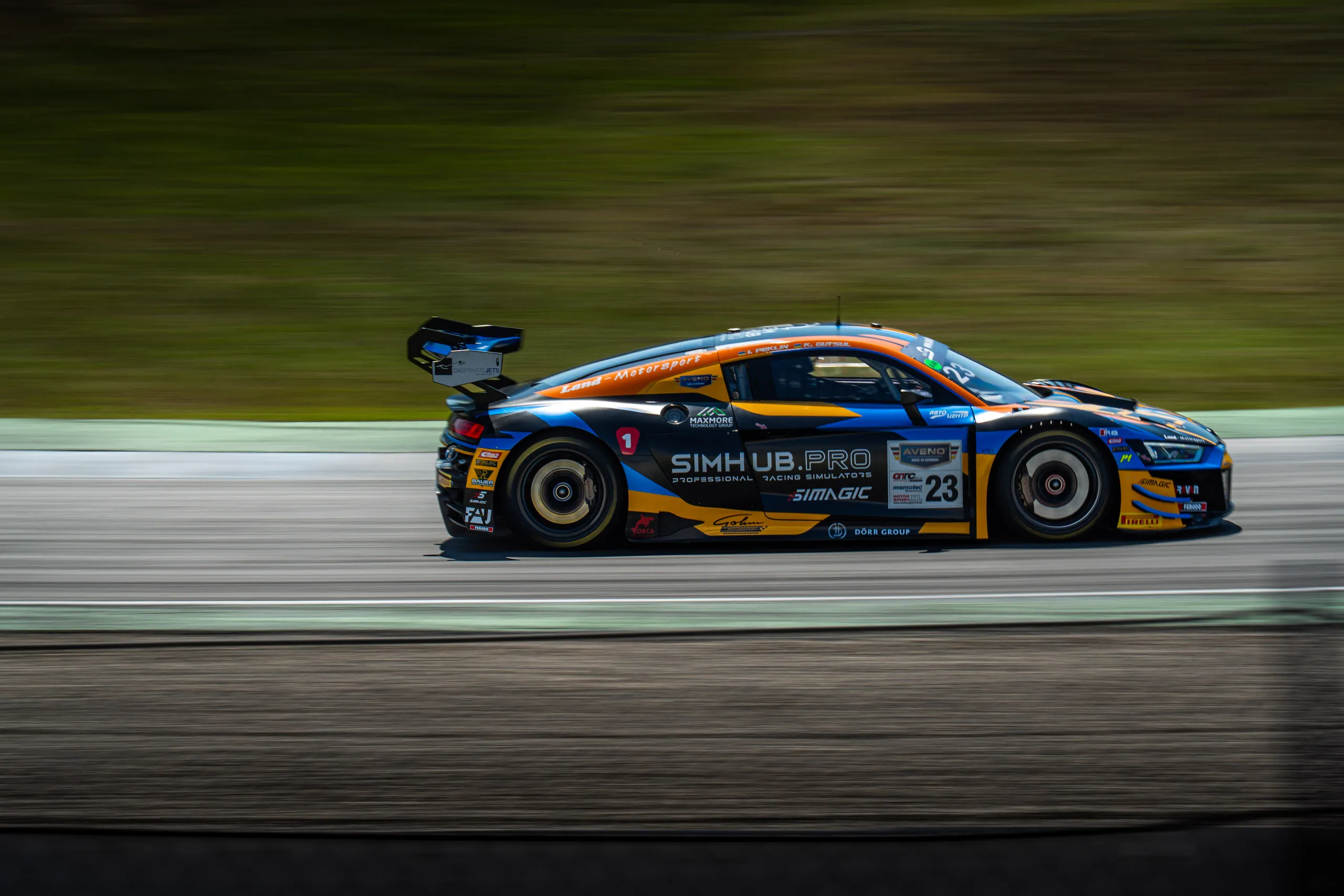 The Land-Motorsport Audi R8 LMS GT3, bearing start number 23, is shown from the side as it races down the track; the words “SIMHUB.PRO” are visible on the driver’s door, and the background blurs into green stripes.