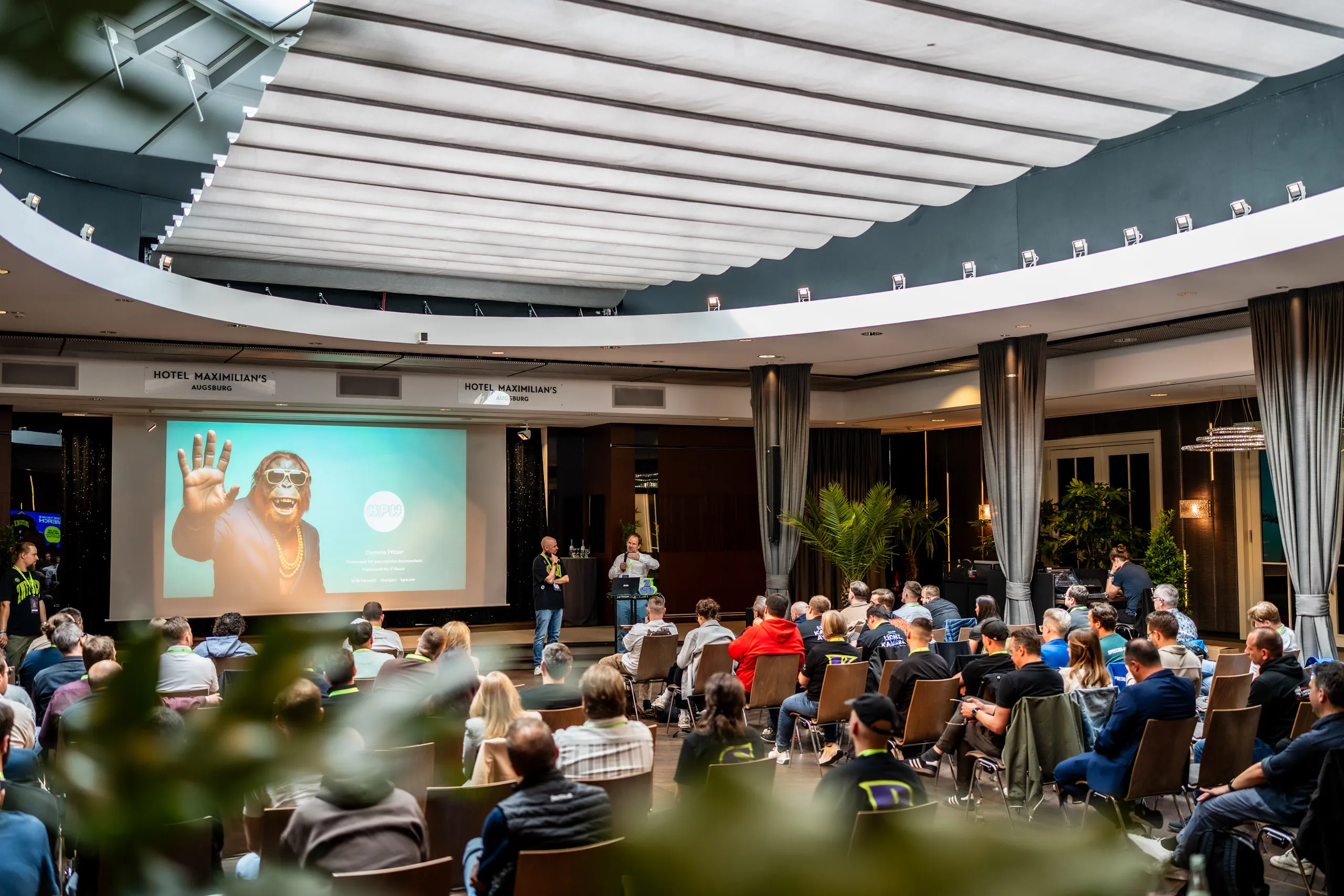 BildbeschBlick über das volle Publikum in den Saal des Hotel Maximilian's in Augsburg während eines Vortrags beim Zwetschke Community Day 2026.reibung
