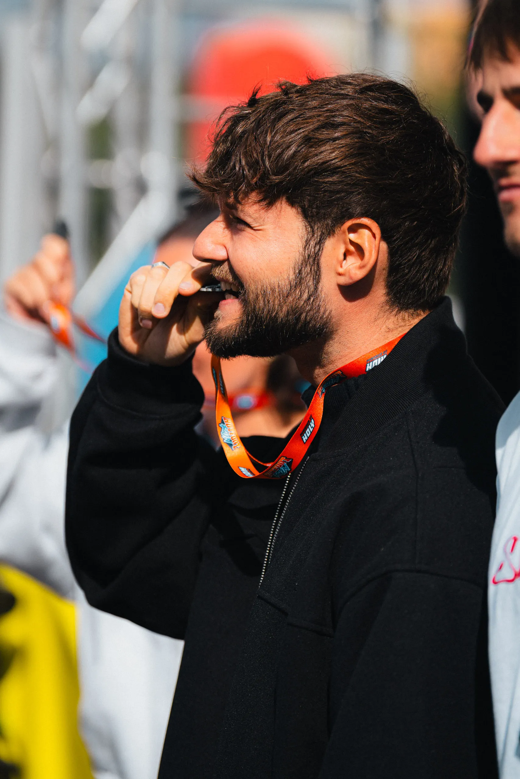 Nicolas Lazaridis (inscope21), seen in profile, bites his medal, hanging from an orange Hotfoot Run lanyard.
