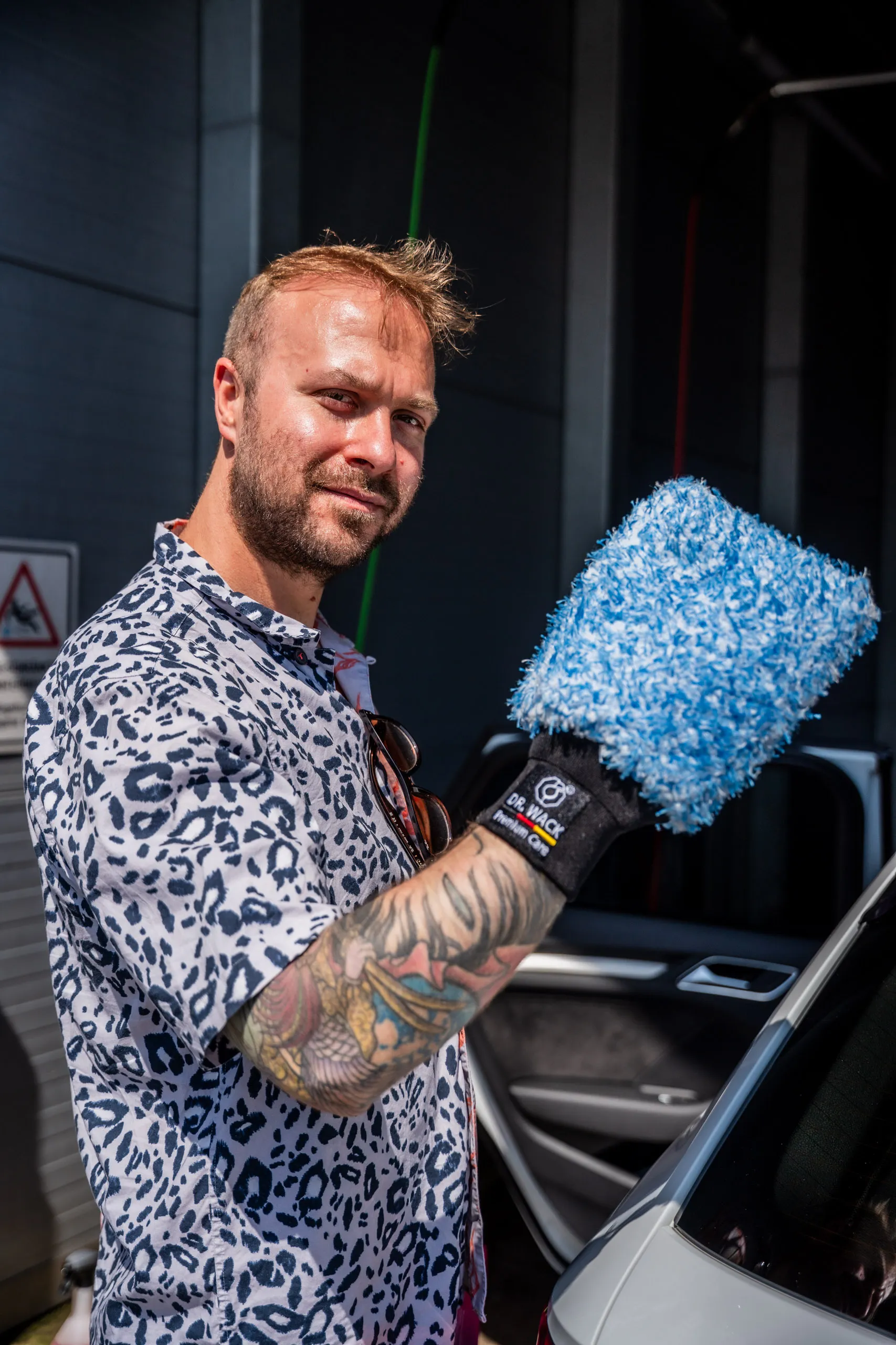 Raphael Siegmund wearing a blue Dr. Wack wash mitt at the open driver’s door of a car.