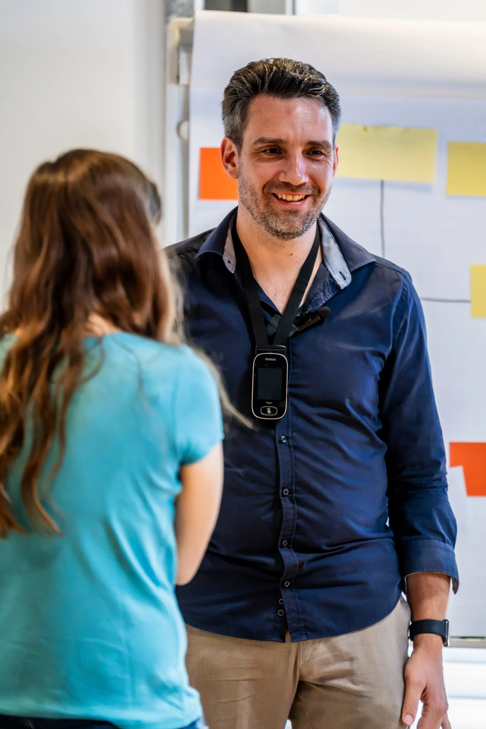 Daniel Musizza talking with a colleague from the association during his talk at the besser sehen trade fair, in front of a pinboard with moderation cards.