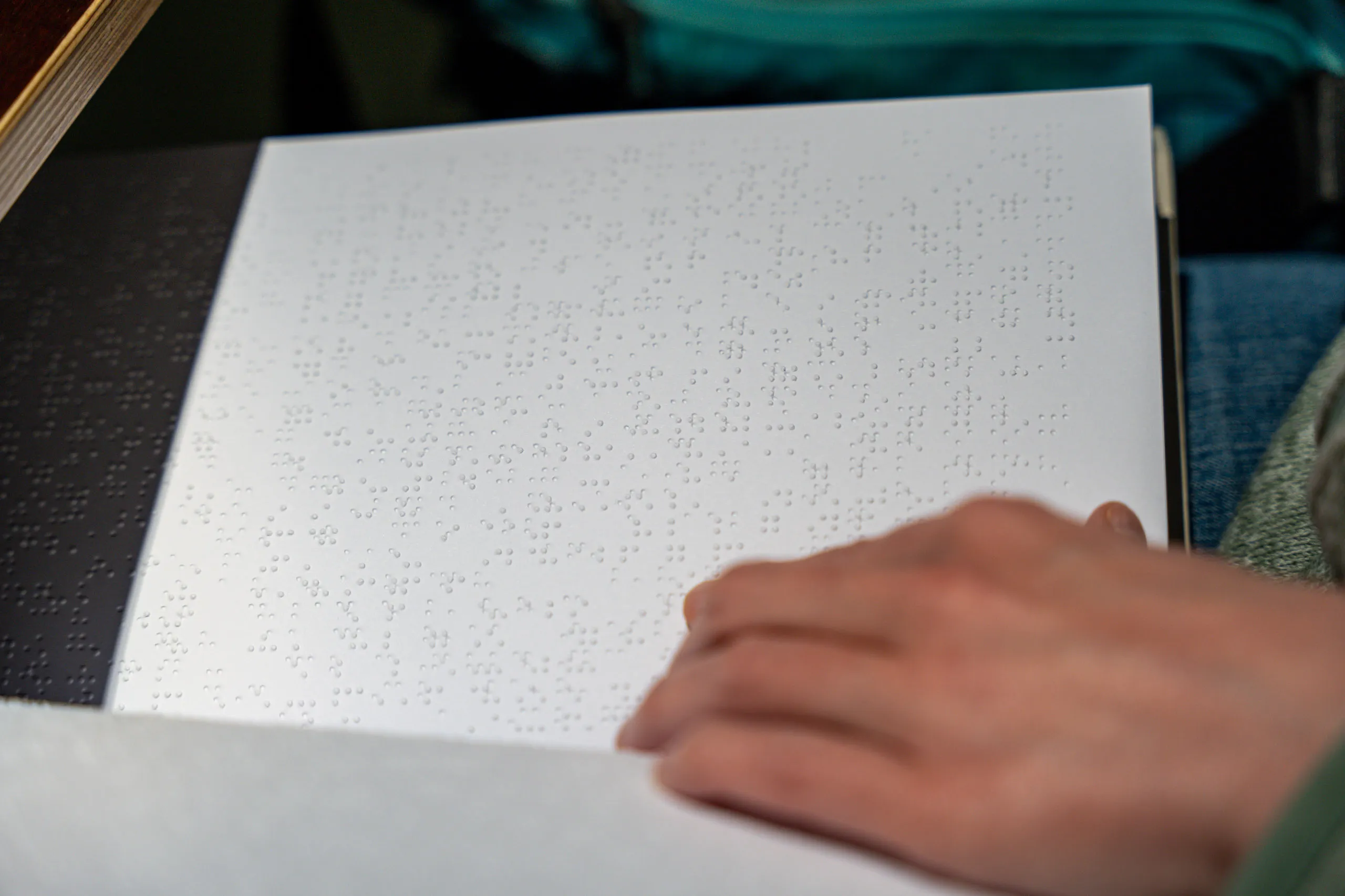 A hand reading a page of braille.